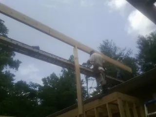 Carpenter setting a ridge beam over a new addition frame — Ice Dam Removal by Roofing Brothers in Lucedale