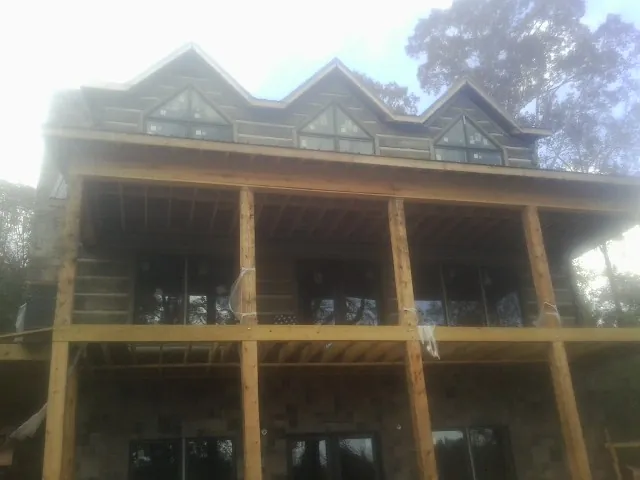 Dormers and porch framing on a large log home under construction — Roof Coating work by our crew in Lucedale