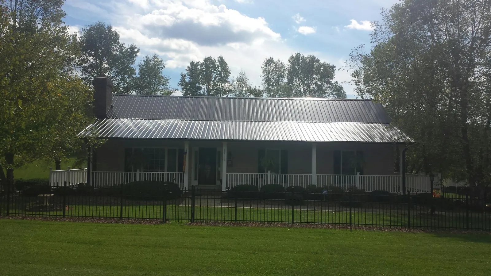 Gray metal roof on a brick ranch with a full width front porch — Gutter Guard Installation work by our crew in Lucedale