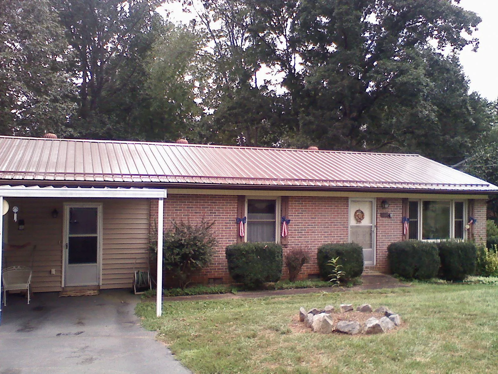 Bronze metal roof and carport on a brick ranch home — Roof Repair work by our crew in Lucedale