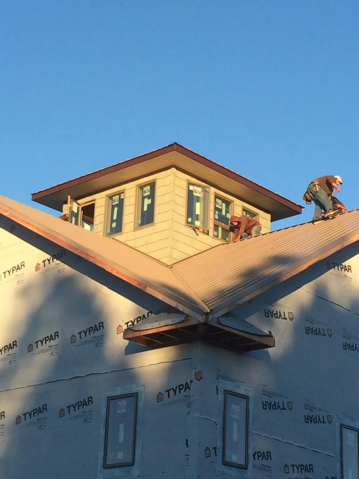 Roofers working around a rooftop cupola on a new metal roof at sunset — Roof Waterproofing in Lucedale by Roofing Brothers